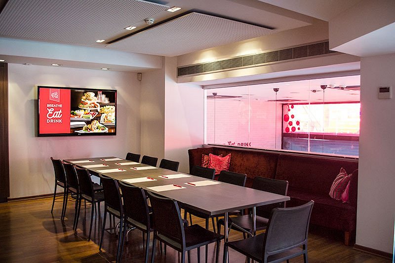 The private conference room at Presse Café Stavrou with boardroom seating and wall-mounted screen